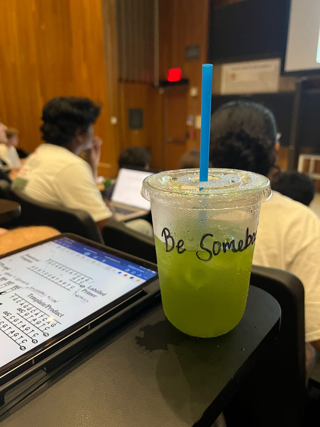 A cup marked Be Somebody, sitting on a desk in the middle of a lecture